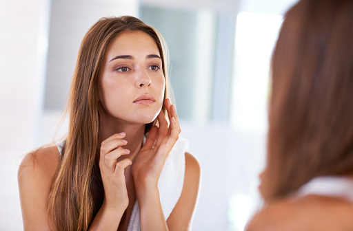 Concerned woman looking in the mirror and touching her face