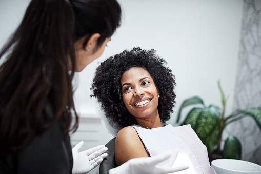 Black woman smiles at dentist after dental exam at Irvine Dentistry.