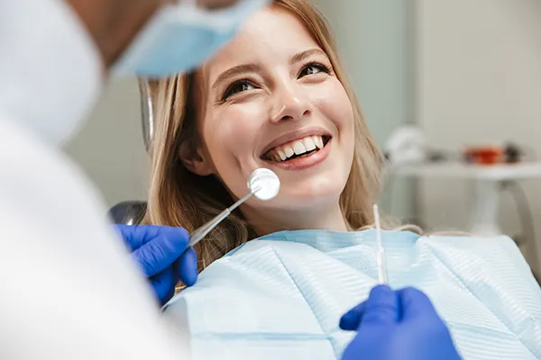 White female patient happily waiting in a dental chair for her dentist to begin her routine dental exam