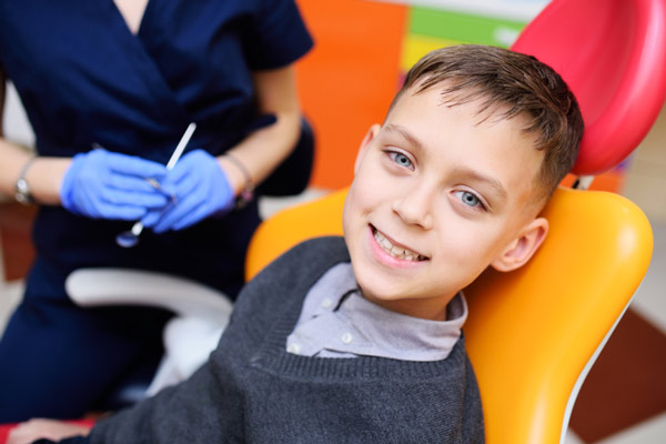 Young boy sitting in dental chair and smiling.